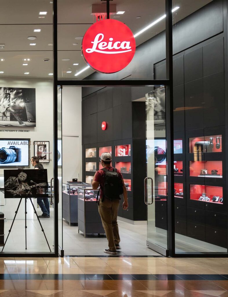 Fachada externa de uma loja da Leica num Shopping internacional com cliente entrando